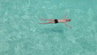 Teenager has a rest on turquoise transparent water of ocean