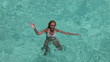 The happy woman in the sea waves to us greeting a hand