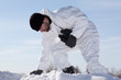 Wounded soldier in white camouflage sneaking through the mountai