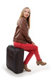 Girl sitting on a suitcase, isolated on white background