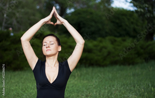Photo: Young woman doing yoga exercises outdoors Young woman doing yoga exercises outdoors