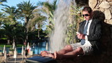 Young businessman using smartphone in exotic resort