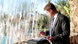 Businessman with tablet and documents stand by the waterfall