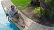 Happy young man with tablet computer sitting by the pool