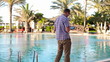 Happy young man with tablet computer walking by the pool