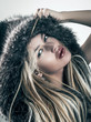fashion portrait of attractive blonde woman in fur coat hood