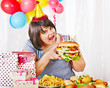 Woman eating hamburger at birthday.