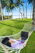 Photo: Asian girl work in hammock with laptop at beach Asian girl work in hammock with laptop at beach
