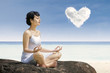 Photo: Attractive woman exercise yoga under love cloud at beach Attractive woman exercise yoga under love cloud at beach