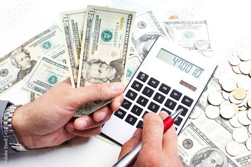 Photo: Hand with calculator and money. Hand with calculator and money.