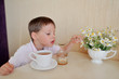 Photo: little boy drinks tea and eats with a spoon and honey on the tab little boy drinks tea and eats with a spoon and honey on the tab