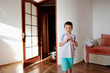 little boy in blue shorts standing in the bright sun room