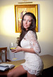 Sensual elegant young woman in white dress holding  a wine glass
