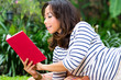 Asian woman at home in garden reading book