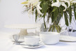 White breakfast table setting with lily flowers