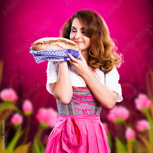 Photo: junge Frau im Dirndl bietet ein Brot an junge Frau im Dirndl bietet ein Brot an