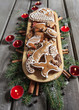 Gingerbread cookies on wooden tray among fir branches and red ca