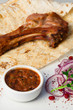Meat on the bone with onions, served with sauce