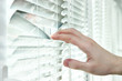 Someone looking out of window opening blinds