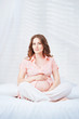Pregnant woman sit on bed