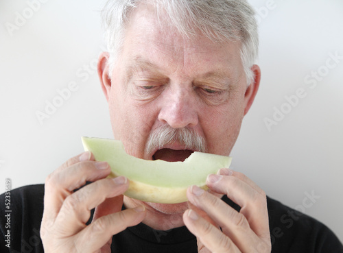 Photo: older man eating melon slice older man eating melon slice