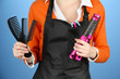 Hairdresser in uniform with working tools, on color background