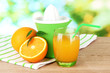 Citrus press, glass of juice and ripe oranges