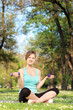 Photo: Young female exercising with dumbbells in park Young female exercising with dumbbells in park