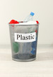 Assorted trash in bucket on room background
