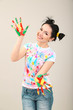 Young pretty painter with hands in paint, on gray background
