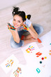 Young pretty painter with hands in paint, on gray background