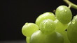bunch of green grapes on a black background with water drops