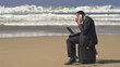 Angry businessman with cellphone and laptop on the beach