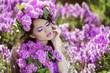 Beautiful young woman in lilac flowers, outdoors portrait