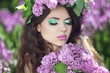 Beautiful young woman in lilac flowers, outdoors portrait