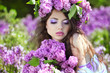 Beautiful young woman in lilac flowers, outdoors portrait
