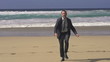 Excited businessman on beach raising hands to the sky