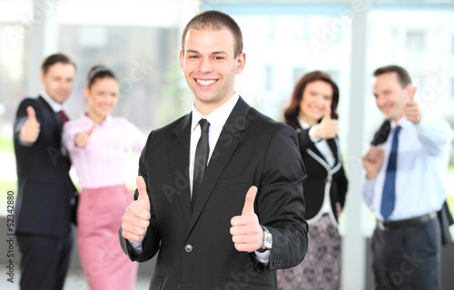 Photo: Cheerful business man with team giving you thumbs up Cheerful business man with team giving you thumbs up