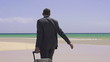 Businessman with suitcase walking on exotic beach, super slow mo