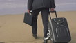 Businessman with suitcase walking on beach, super slow motion