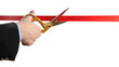 Man's hand cutting red ribbon with pair of scissors isolated