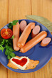 Sausage, greens, tomato on plate on wooden table