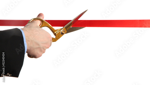 Photo: Man's hand cutting red ribbon with pair of scissors isolated Man's hand cutting red ribbon with pair of scissors isolated