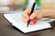 Hand signing in notebook, on bright background