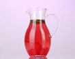 Cherry drink in pitcher on purple background.
