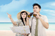 Asian couple using binoculars at beach