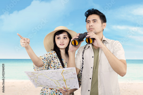 Photo: Asian couple using binoculars at beach Asian couple using binoculars at beach