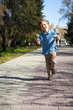 Boy running along road in park