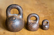 Three small calibration weights on wooden background