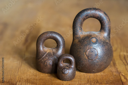 Photo: Three small calibration weights on wooden background Three small calibration weights on wooden background